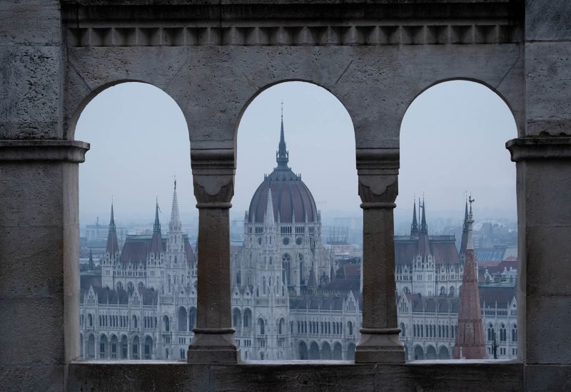 Parliament building in Budapest, framed by an archway.